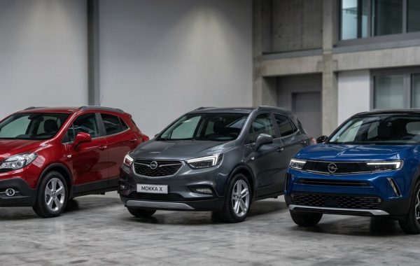 Vizualna usporedba evolucije dizajna SUV modela Opel Mokka. Postavljeni su s tri-četvrt prednje strane: s lijeve strane originalna crvena Mokka, u sredini siva Mokka X, a s desne strane najnovija plava generacija s prepoznatljivim 'Opel Vizor' licem. Vozila su u izložbenom salonu ili studiju.
